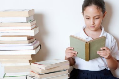 genç kız evde kitap yığınları çevrelenmiş bir kitap okuma.