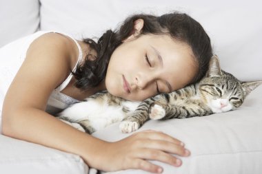 genç kız ve beyaz kanepede evde uyuyan kedi.