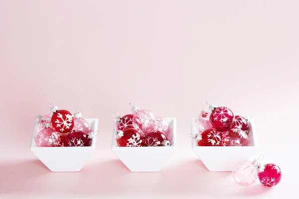 Kleine kerst ballen in kleine recipiënten uitgelijnd op een roze achtergrond. — Stockfoto