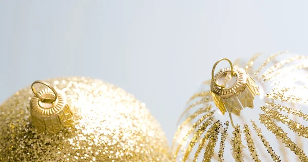 Dois ornamentos de bolas de Natal dourado contra um fundo prateado . — Fotografia de Stock