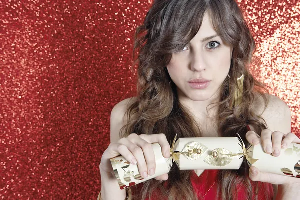 Young attractive woman holding and pulling a Christmas cracker — Stock Photo, Image