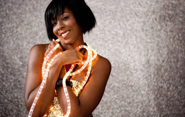 Beautiful black woman holding Christmas fairy lights — Stock Photo, Image