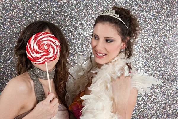 Дві молоді жінки влаштовують вечірку, одягаючи і використовуючи великі цукерки, щоб приховати обличчя однієї . — стокове фото
