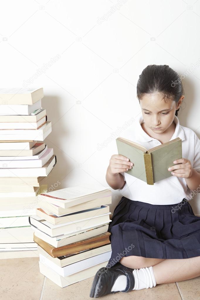 Young school girl reading a book