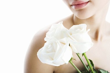 Young attractive woman holding three white roses next to her lips