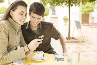 cep telefonu ve kartpostal bir kafede yazma genç Çift