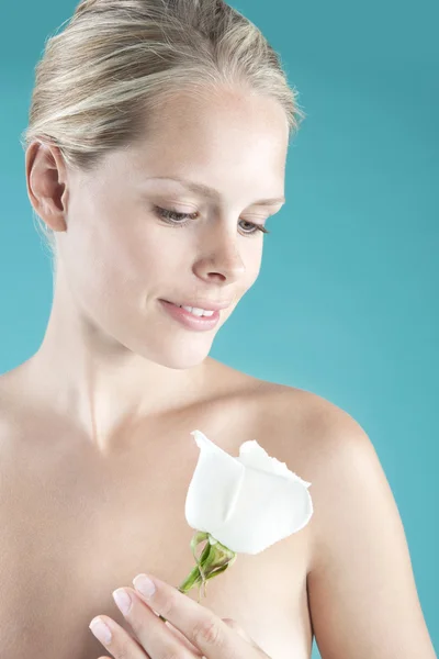 Νεαρό ξανθιά γυναίκα που κρατά ένα λευκό τριαντάφυλλο στα χέρια της. — Φωτογραφία Αρχείου
