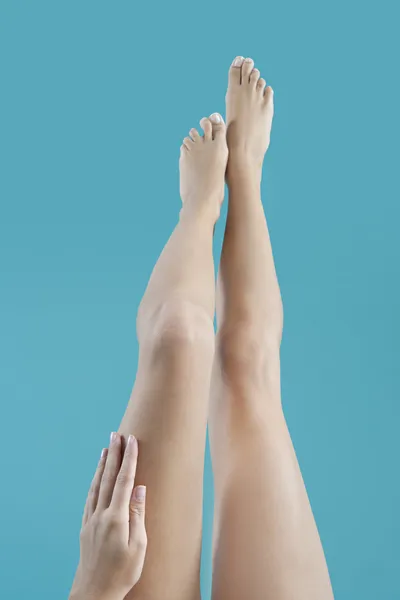 Pernas de mulher nua no ar com a mão tocando-os . — Fotografia de Stock