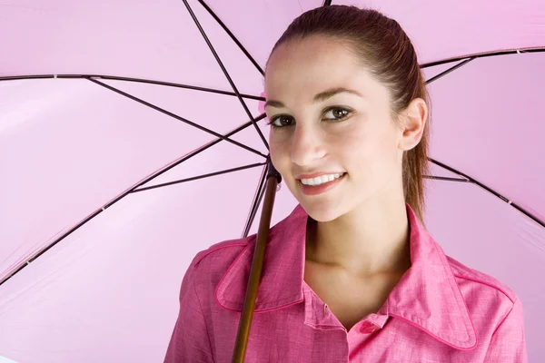 Atraktivní mladá žena na sobě růžový kabát a drží otevřené růžový deštník — Stock fotografie