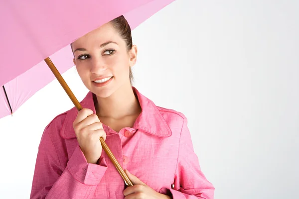 ピンクの雨コートを着て明るいピンクの傘の下で魅力的な若い女性 — ストック写真