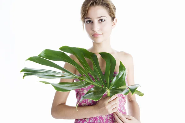 Atrakcyjna młoda kobieta, posiadający duży zielony liści przed jej — Zdjęcie stockowe