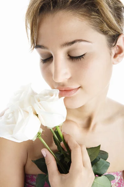 Νέα ελκυστική γυναίκα που κρατά τρία λευκά τριαντάφυλλα, δίπλα από τα χείλη της — Φωτογραφία Αρχείου