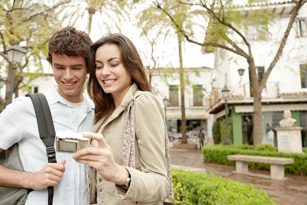 Young couple taking a picture of themselves while on vacation in a picturesque town square — Stock Photo, Image