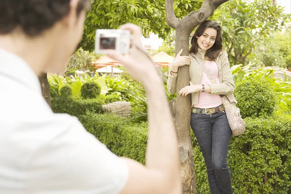 Young man taking a picture of his girlfriend while on vacations in a town square. — Stock Photo, Image