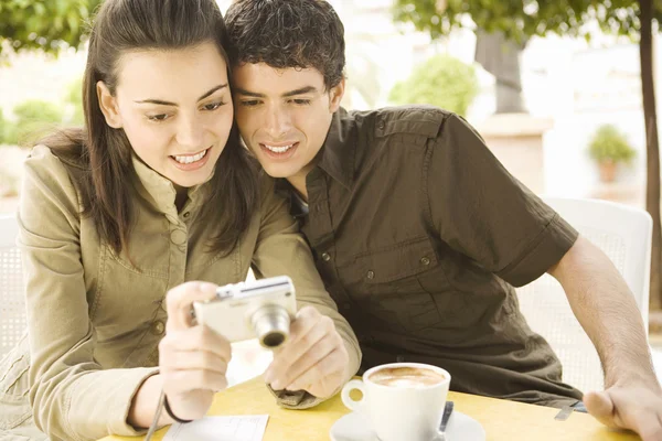 Jovem casal turístico em café visualização de fotos em sua câmera fotográfica digital — Fotografia de Stock