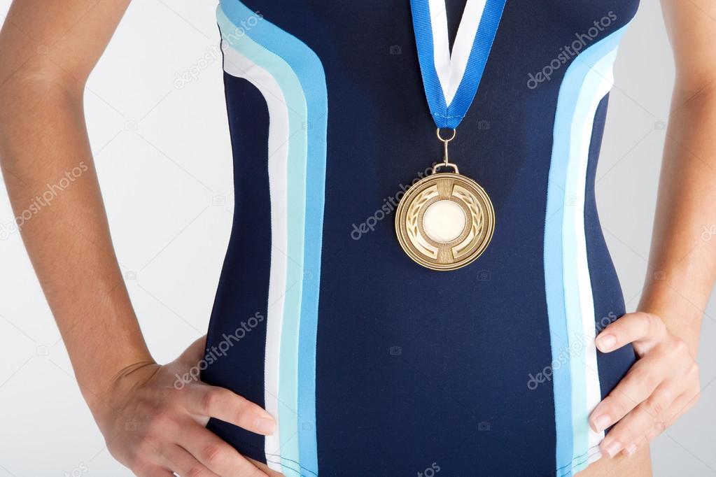 Middle section of an olympic swimmer's body wearing a gold medal