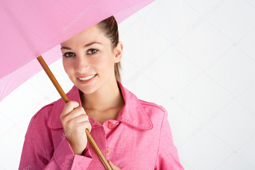 attractive young woman under a bright pink umbrella wearing a pink rain coat