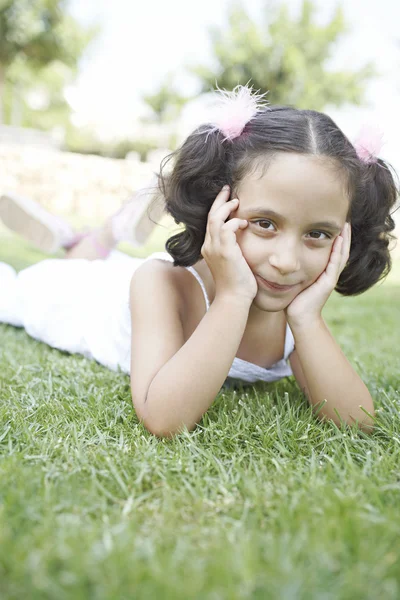 Giovane ragazza sdraiata su erba verde — Foto Stock