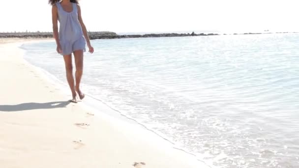 Young girl walking along the shore of a Mediterranean beach. — Stock Video