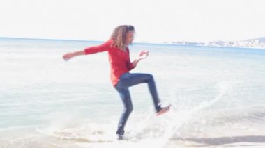 Deniz suyu tekme ve şakacı bir pastoral plaj etrafında dönen genç kız.