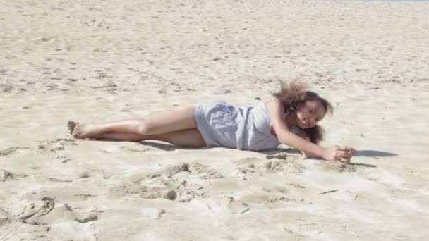Meisje rollen op het zand van een witte strand. — Stockvideo