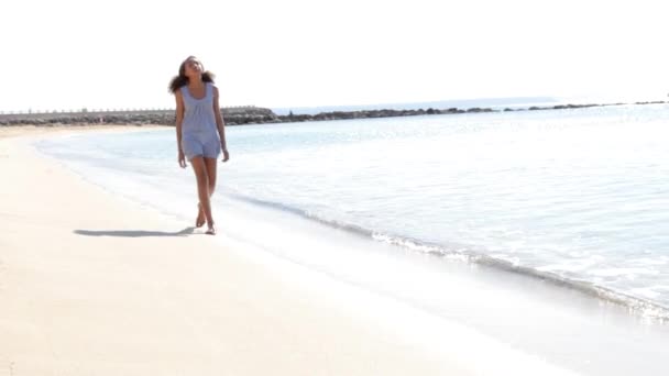 Giovane ragazza si avvicina alla macchina fotografica, passeggiando lungo la spiaggia — Video Stock