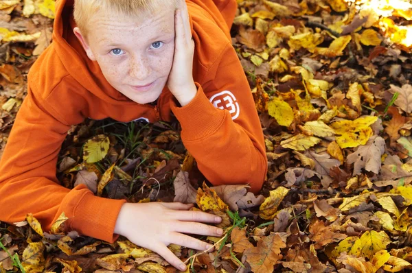 Boy with freckles laying down on leaves — Stock Photo, Image