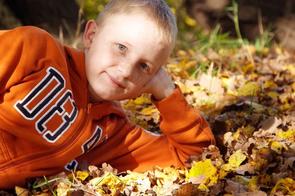 Garçon avec des taches de rousseur couché sur les feuilles — Photo