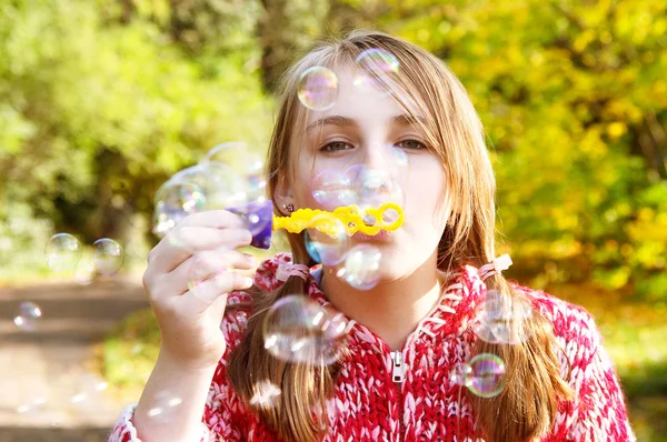 Girl in a park blowing soap bubbles — Stock Photo, Image