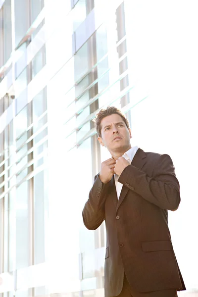 Businessman standing by a modern glass office — Stock Photo, Image