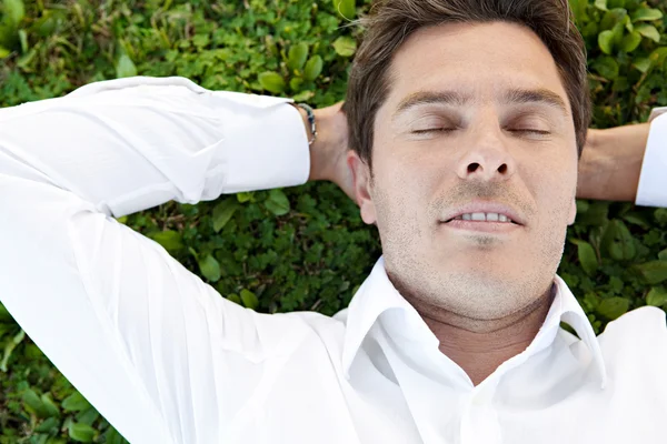 Businessman laying down on green grass — Stock Photo, Image