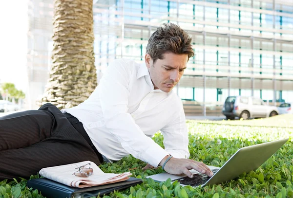 Businessman laying down on green grass — Stock Photo, Image