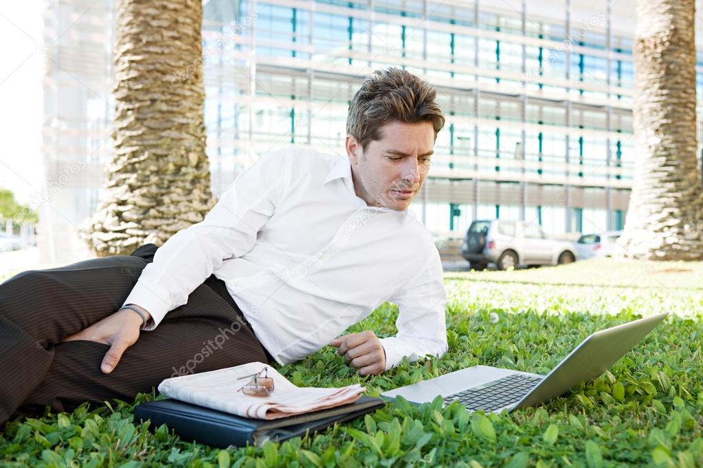 Businessman laying down on green grass