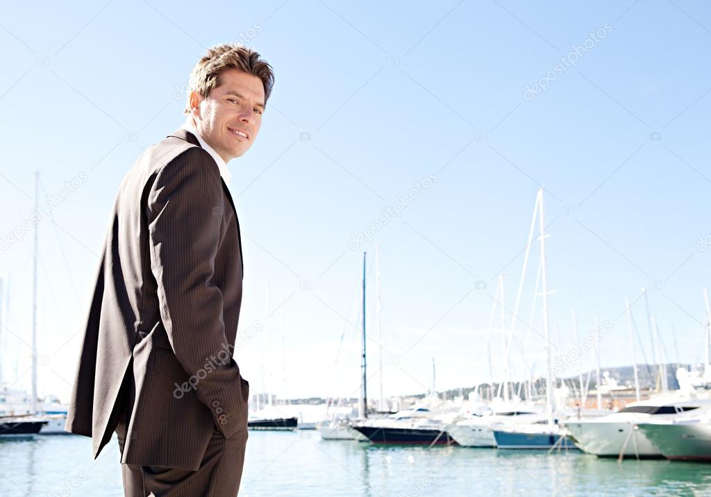 Businessman standing by moored sailing boats