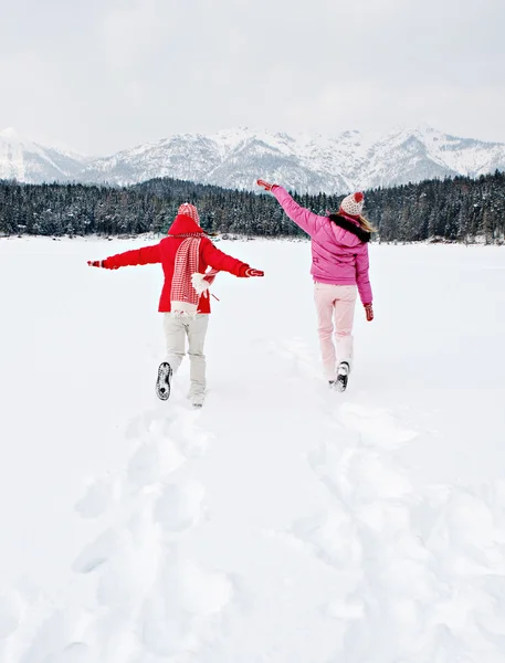 Two women running together across a frozen lake — Stock Photo, Image
