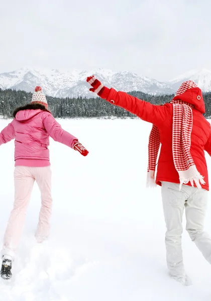 Two women running together across a frozen lake — Stock Photo, Image