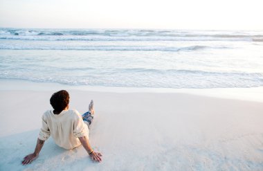 Young man sitting on beach clipart