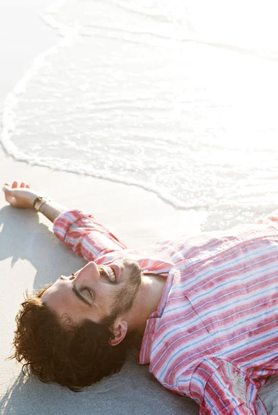 Uomo sdraiato sulla riva del mare — Foto Stock