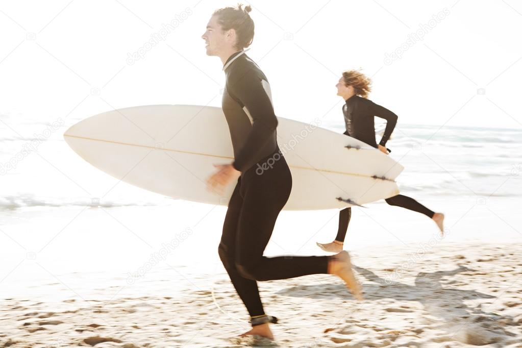 Surfers running together