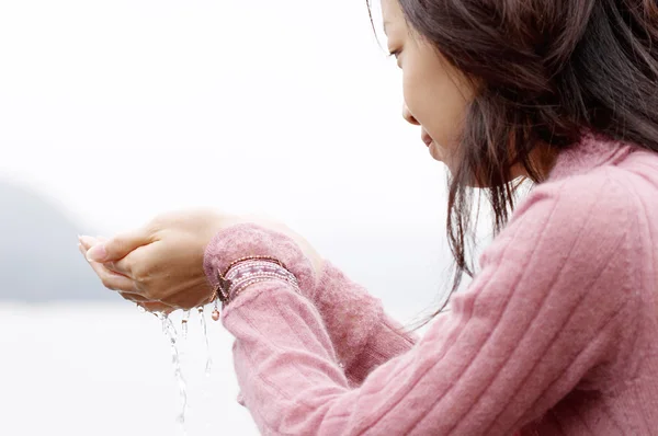 Jeune femme debout près d'un lac — Photo