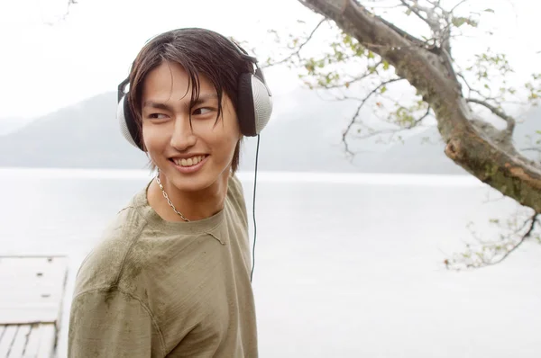アジア人の男性が彼のヘッドフォンで音楽を聴く — ストック写真
