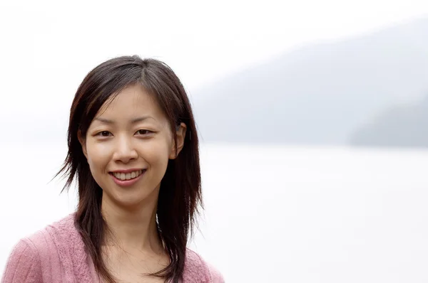 Mujer sonriendo mientras visita un hermoso lago — Foto de Stock