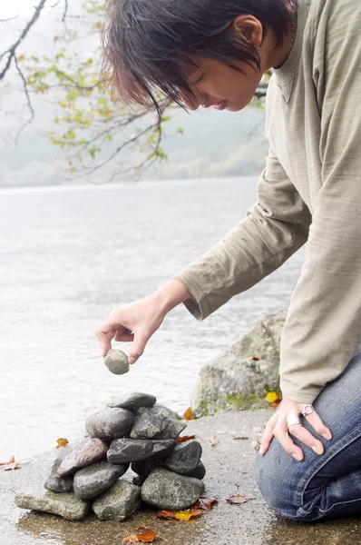 Man building a stone pyramid pile — Stock Photo, Image