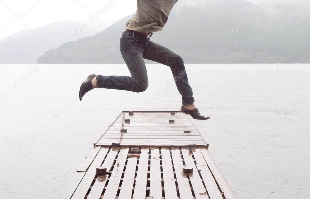 Man jumping on a wooden pier