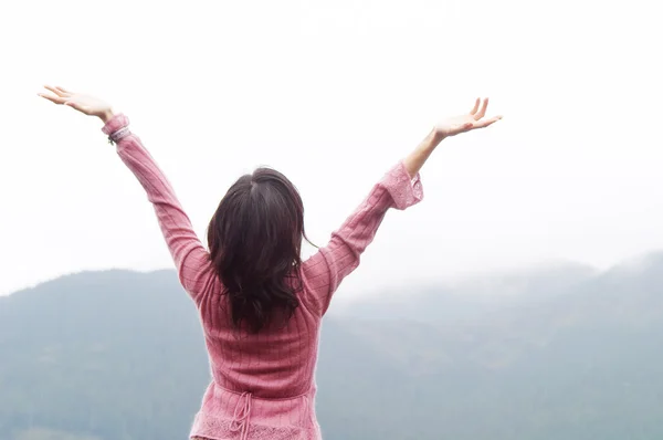 Woman standing by a lake and mountains — Stock Photo, Image