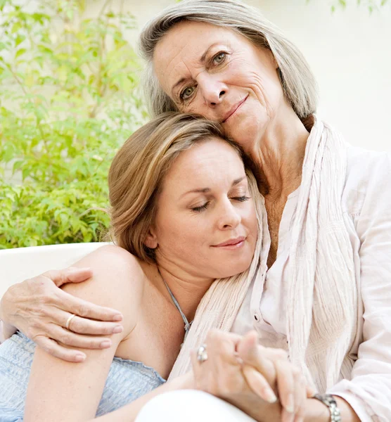 Daughter and her mother lounging together on a sofa — Stock Photo, Image