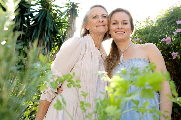 Mother and daughter standing in home garden — Stock Photo, Image