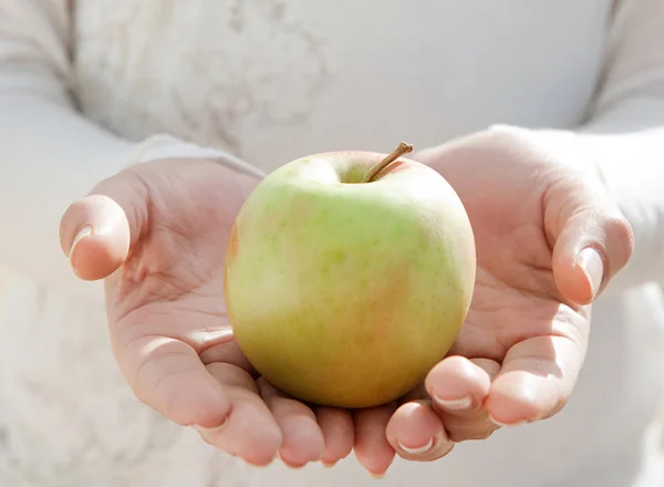 Woman hands holding an organic green apple — Stock Photo, Image