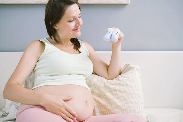 Zwangere vrouw met paar blauwe bootees — Stockfoto