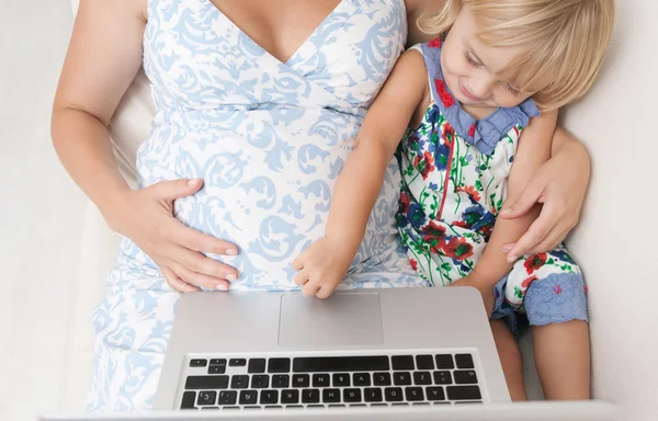 Mãe grávida e filha infantil com laptop — Fotografia de Stock